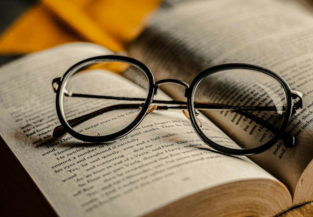 Pages of an open mystery novel with reading glasses